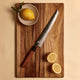 Yuzu Knives Japanese steel serrated bread knife on a walnut cutting board with lemons