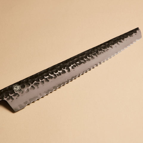 Close-up of serrated bread knife blade with kurouchi hammered finish