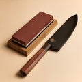 Gyuto knife in saya sheath next to dual-sided sharpening stone