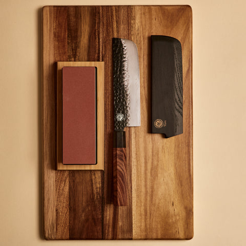 Yuzu Knives Japanese steel Nakiri starter kit — knife, sharpening stone, and saya on a cutting board