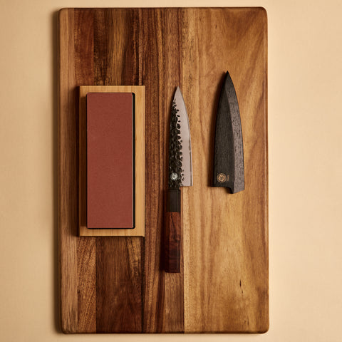 Yuzu Knives Japanese steel Petty starter kit — knife, sharpening stone, and saya on a cutting board