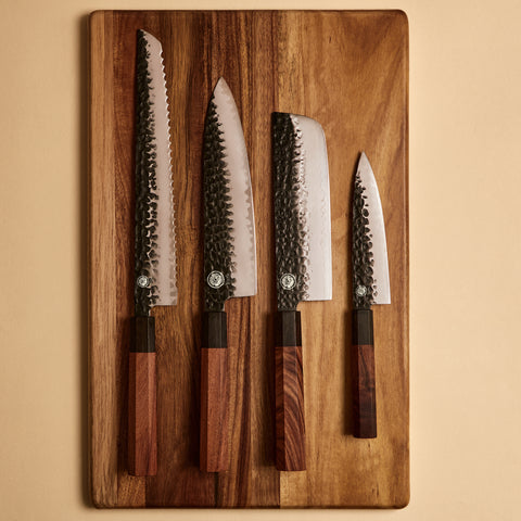 Yuzu Knives Japanese steel four knife set — Bread, Gyuto, Nakiri, and Petty on a cutting board