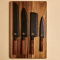 Four knives in wooden saya sheaths on a walnut cutting board