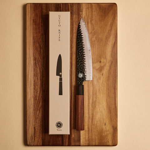 Gyuto knife next to its gift box packaging on a cutting board