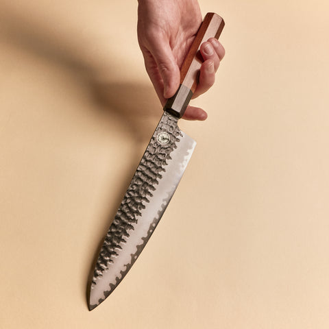 Hand holding a Gyuto knife showing the kurouchi blade and wa handle