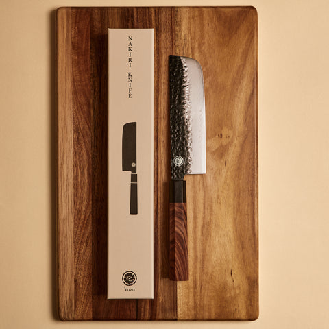 Nakiri knife next to its gift box packaging on a cutting board