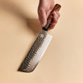 Hand holding a Nakiri knife showing the flat kurouchi blade