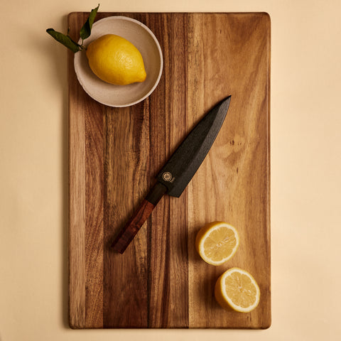 Petty knife in wooden saya knife sheath on a cutting board with lemons