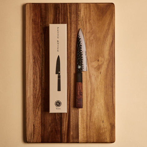 Petty knife next to its gift box packaging on a cutting board