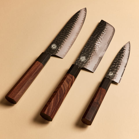Three Japanese steel knives arranged showing kurouchi blades and wa handles