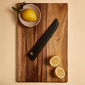 Bread knife saya sheath on a cutting board with lemons