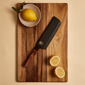 Nakiri knife in its wooden saya sheath on a cutting board with lemons